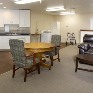 A cozy living space with a kitchen area, round table, upholstered chairs, and a sofa.