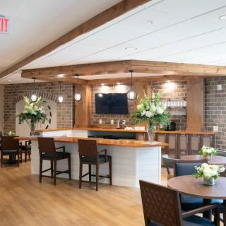A modern bar and restaurant interior with wood and brick elements, featuring seating areas and a television.