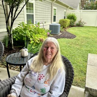 A woman enjoys a peaceful moment in her garden, surrounded by greenery.