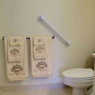 A clean bathroom featuring neatly arranged towels and a safety grab bar next to the toilet.