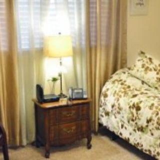 A cozy bedroom with floral bedding, a wooden nightstand, and a lamp.