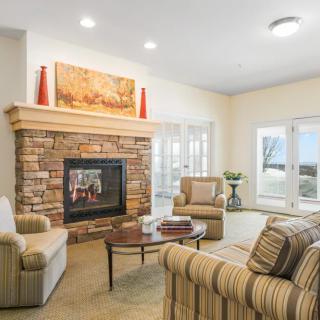 A cozy living room featuring a stone fireplace, comfortable seating, and large windows allowing natural light to fill the space.