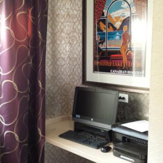 A cozy workspace featuring a computer, printer, and an artistic poster.