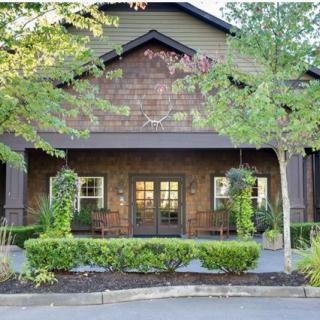 A charming building with a wooden exterior surrounded by trees and neatly trimmed bushes.