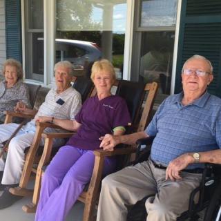 A group of elderly people sitting on rocking chairs on a porch, enjoying each other's company.