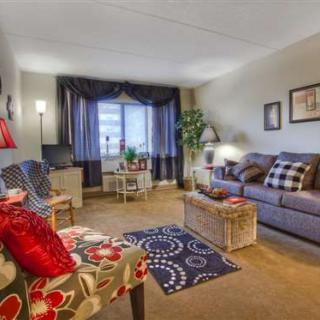 A cozy living room with a sofa, armchair, and colorful decor.