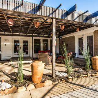 A charming outdoor patio featuring a pergola with terracotta pots and plants, creating a shaded seating area.