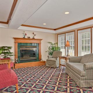 A cozy living room with a fireplace, armchairs, and large windows providing natural light.