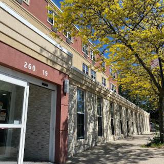A sunny day showcasing a building's entrance with trees lining the street.