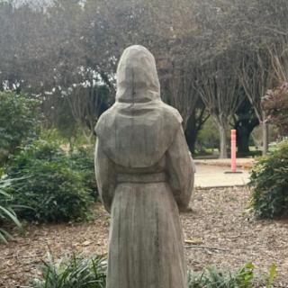 A statue in a garden surrounded by greenery and trees.
