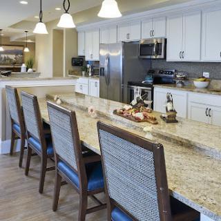 A modern kitchen featuring a granite countertop with bar stools and contemporary appliances.