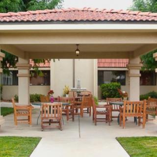 Outdoor patio area with wooden seating under a gazebo.