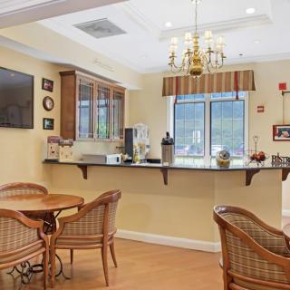 Cozy dining area with wicker chairs and tables, featuring a counter with a coffee maker and a mounted television.