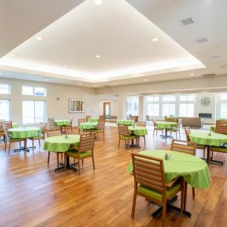 A spacious and well-lit dining area with green tablecloths on wooden tables.
