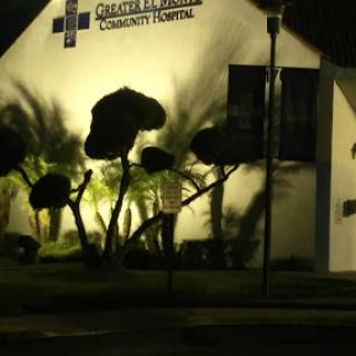 A well-lit community hospital at night, surrounded by illuminated trees.