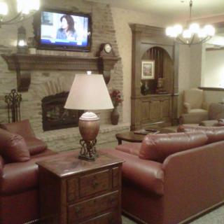A cozy living room with leather sofas, a fireplace, and a television mounted above.