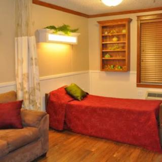 A cozy bedroom with a single bed, sofa, and wooden flooring.