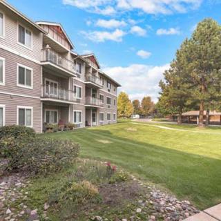 A residential apartment building with well-maintained grass and trees.