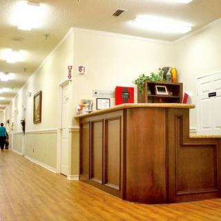 An empty reception desk in a brightly lit hallway with wood flooring.