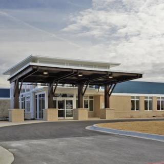 A modern building with a prominent entrance and a cloudy sky overhead.