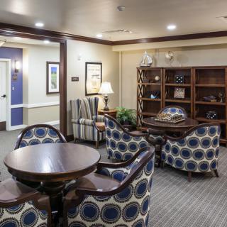 A cozy living room area with patterned chairs, a round table, and a bookshelf.