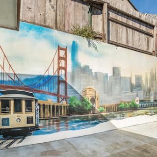 A vibrant mural depicting the Golden Gate Bridge and a classic San Francisco cable car, showcasing the city's iconic skyline.