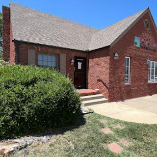 A charming brick house with a neatly maintained front yard under a clear blue sky.