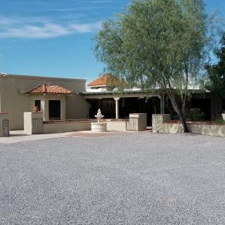 A view of a building with a courtyard featuring a tree and a fountain under a clear blue sky.