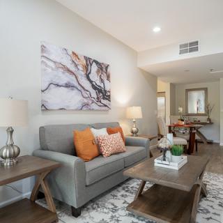 A modern living room featuring a gray sofa, wooden coffee table, and decorative artwork on the wall.