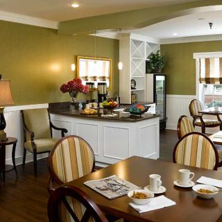 A cozy dining area with a breakfast setup, featuring tables, chairs, and a buffet counter.