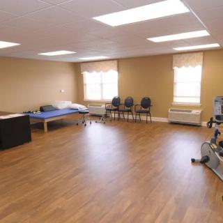 A spacious physical therapy room equipped with exercise machines and seating.