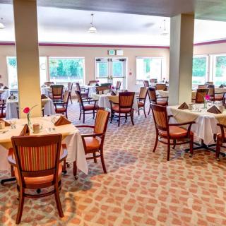 An elegant and empty restaurant dining room with neatly set tables and chairs.