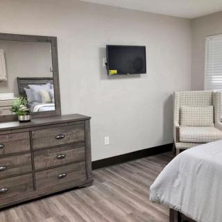 A modern bedroom with a dresser, mirror, and mounted TV.