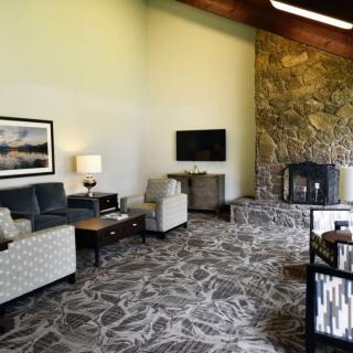 A modern living room featuring a stone fireplace, comfortable seating, and a mounted television.
