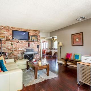 A cozy living room featuring a brick wall with a mounted television, comfortable seating, and colorful decor.