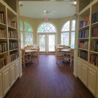 A cozy reading room with large windows, filled with books and comfortable seating.