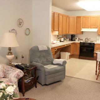 A cozy living room and kitchen area featuring comfortable seating and warm wooden cabinetry.