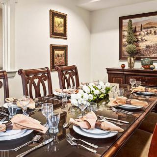 A formal dining room with an elegantly set table, complete with glassware, napkins, and decorative centerpieces.