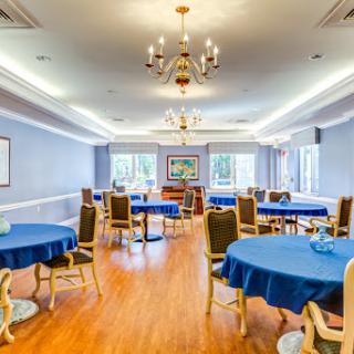 A spacious dining room featuring blue tablecloths and elegant lighting.