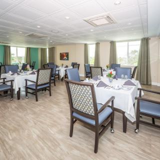 A formal dining room with neatly arranged tables and chairs, featuring elegant table settings and decor.