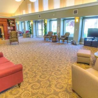 A spacious and bright lobby with comfortable seating, large windows, and a television, designed for relaxation.