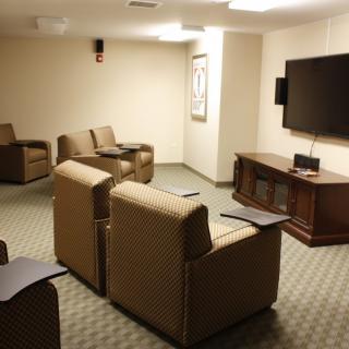 A small conference room with multiple chairs facing a large television.