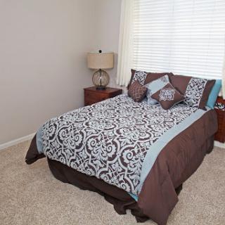 A cozy and stylish bedroom featuring a beautifully made bed with patterned bedding, complemented by a bedside lamp and warm light.