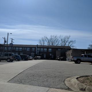 A view of a building surrounded by a parking lot on a clear day.
