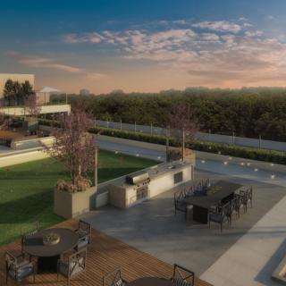 A scenic rooftop with outdoor seating offers a beautiful view of the sunset over the urban landscape.