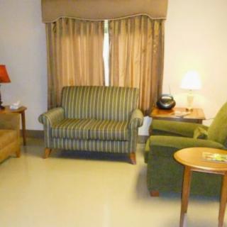 A cozy living room with sofas, armchairs, and a side table with lamps.