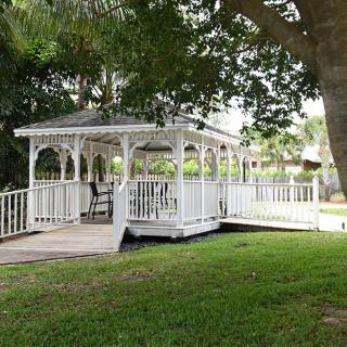A white gazebo surrounded by trees and grass in a park setting.