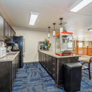 A modern kitchen interior featuring a popcorn machine on the countertop with seating stools and various appliances.
