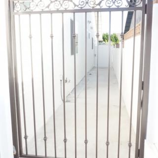 A metal gate providing security to a narrow outdoor pathway.