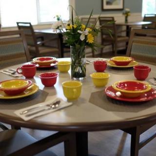 A dining table set with colorful red and yellow dishes, surrounded by chairs in a cozy dining area.